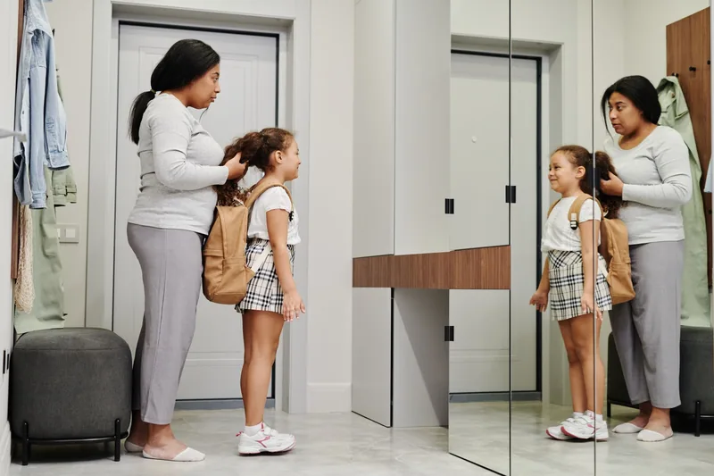 Mother getting her daughter ready for school before the school day starts