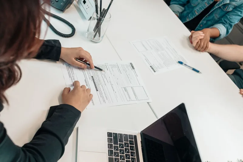 Parent reviewing homeschool registration paperwork at a table with a laptop