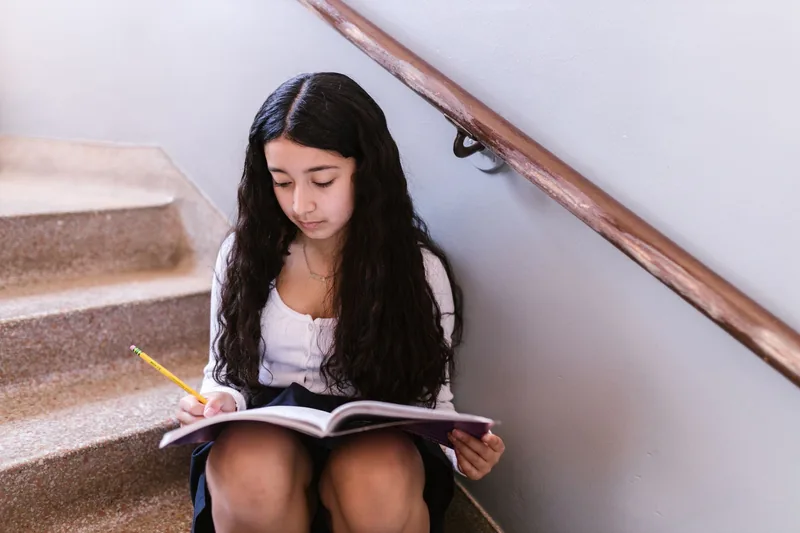 Middle school girl working through homework in a notebook after school